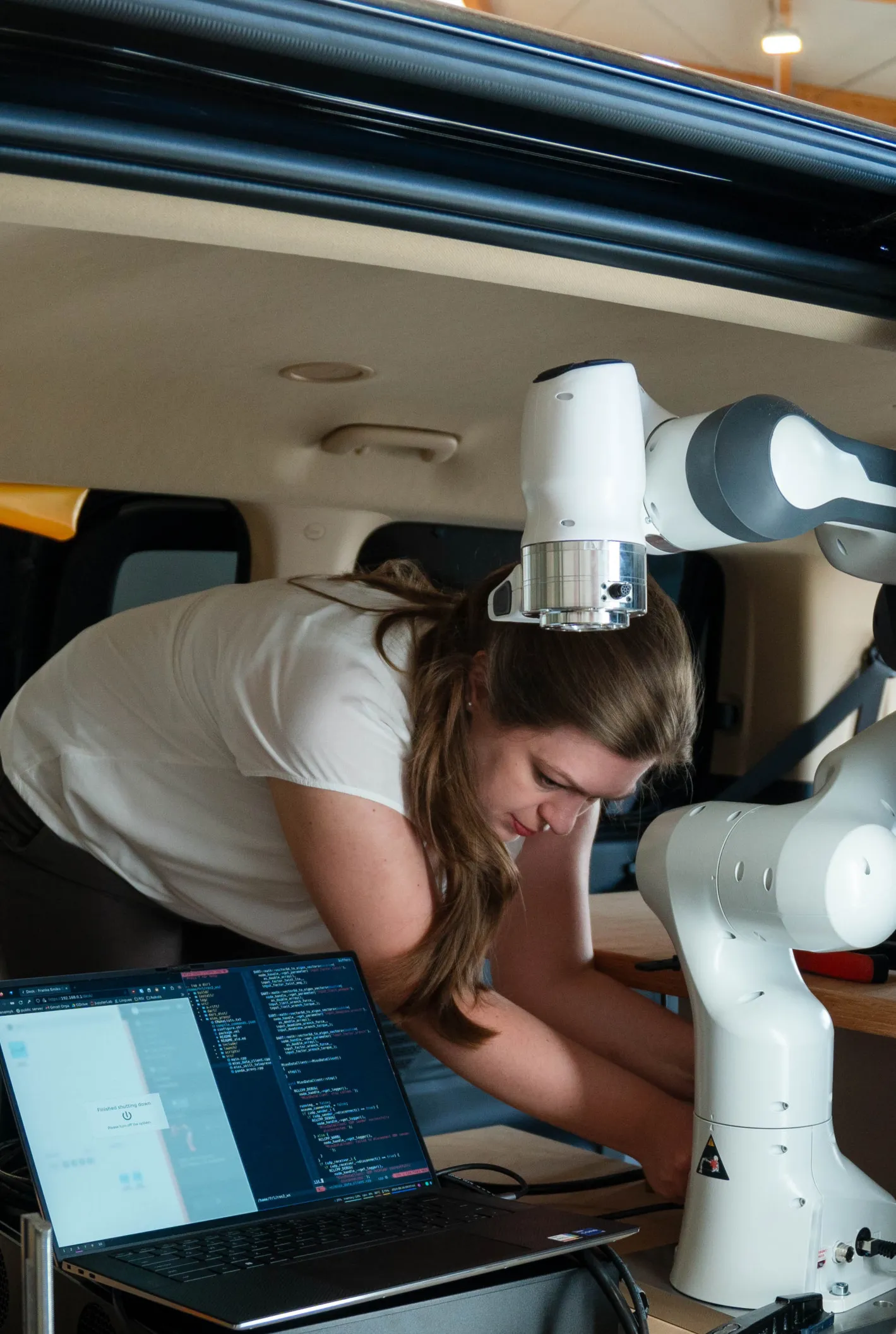 Anna Adamczyk installing a tactile robotic arm in the SVan mobile field laboratory and testing the control interface on a laptop
