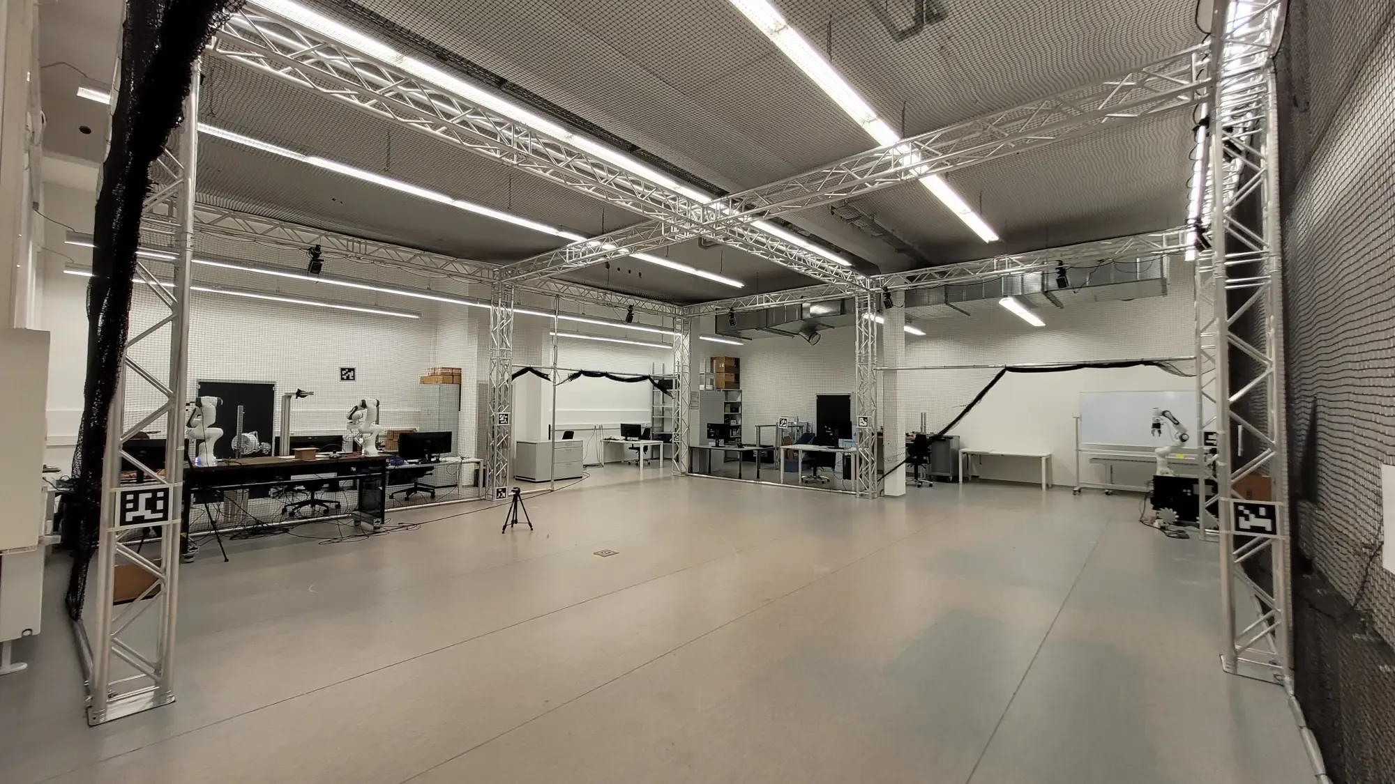 Mobile Systems Arena at TUM MIRMI. It has specialized workstations, various flying robots, and the Mobile Systems Arena. The Arena has a floor area of 81m2, is surrounded by a truss system with mesh and is equipped with a Vicon motion capture system. 